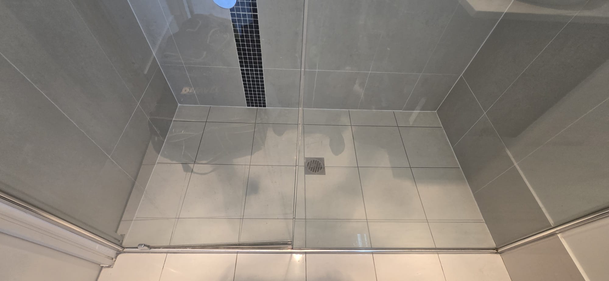Completed shower repair showing the tiled floor and sealed wall junctions